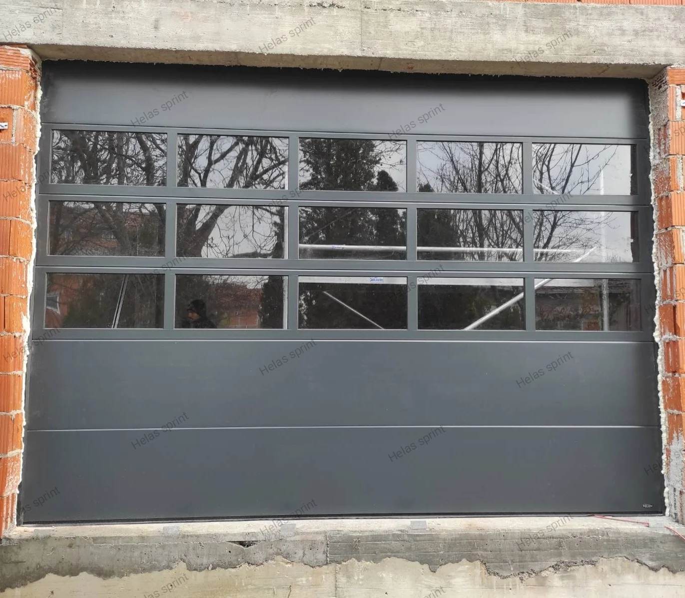 Panorama garažna vrata sa staklenim panelima na objektu od cigle